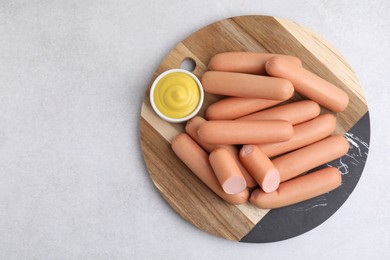 Photo of Delicious boiled sausages and sauce on light gray table, top view. Space for text