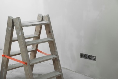 Wooden ladder near wall, space for text