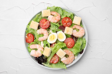 Photo of Delicious Caesar salad with shrimps on white textured table, top view