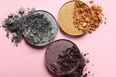 Different crushed eye shadows on pink background, flat lay