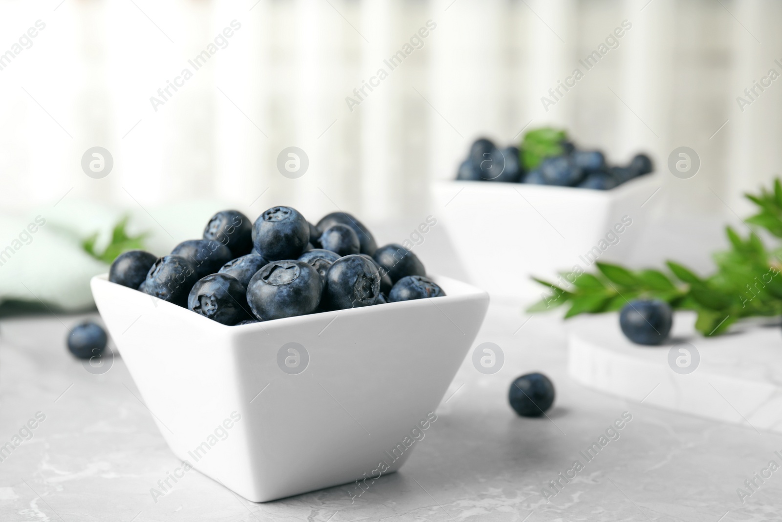 Photo of Bowl of tasty blueberries on grey table, space for text