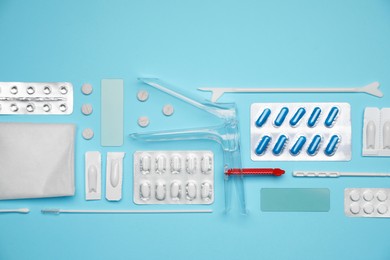Sterile gynecological examination kit and pills on light blue background, flat lay