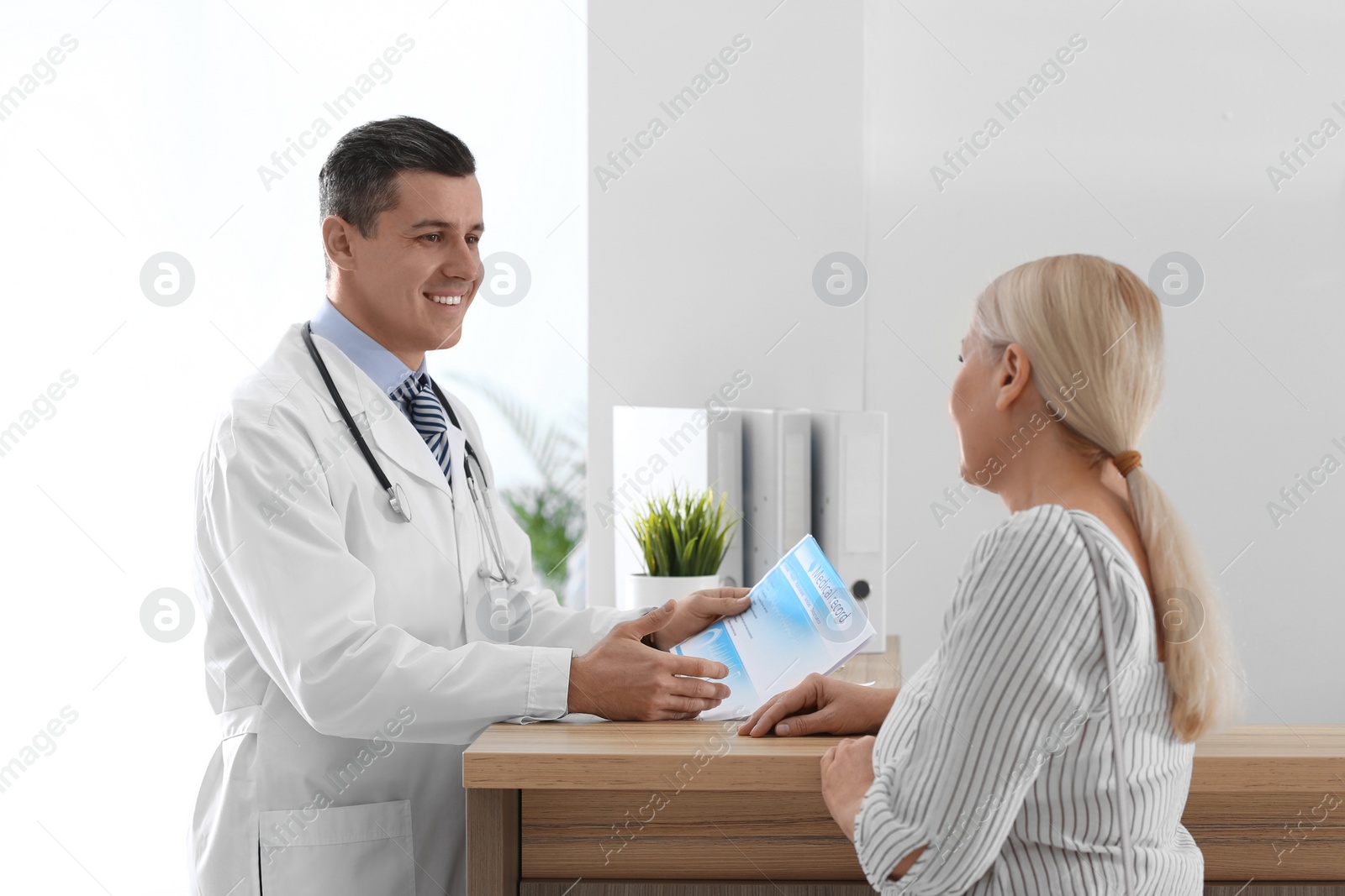 Photo of Doctor talking with patient near reception in hospital