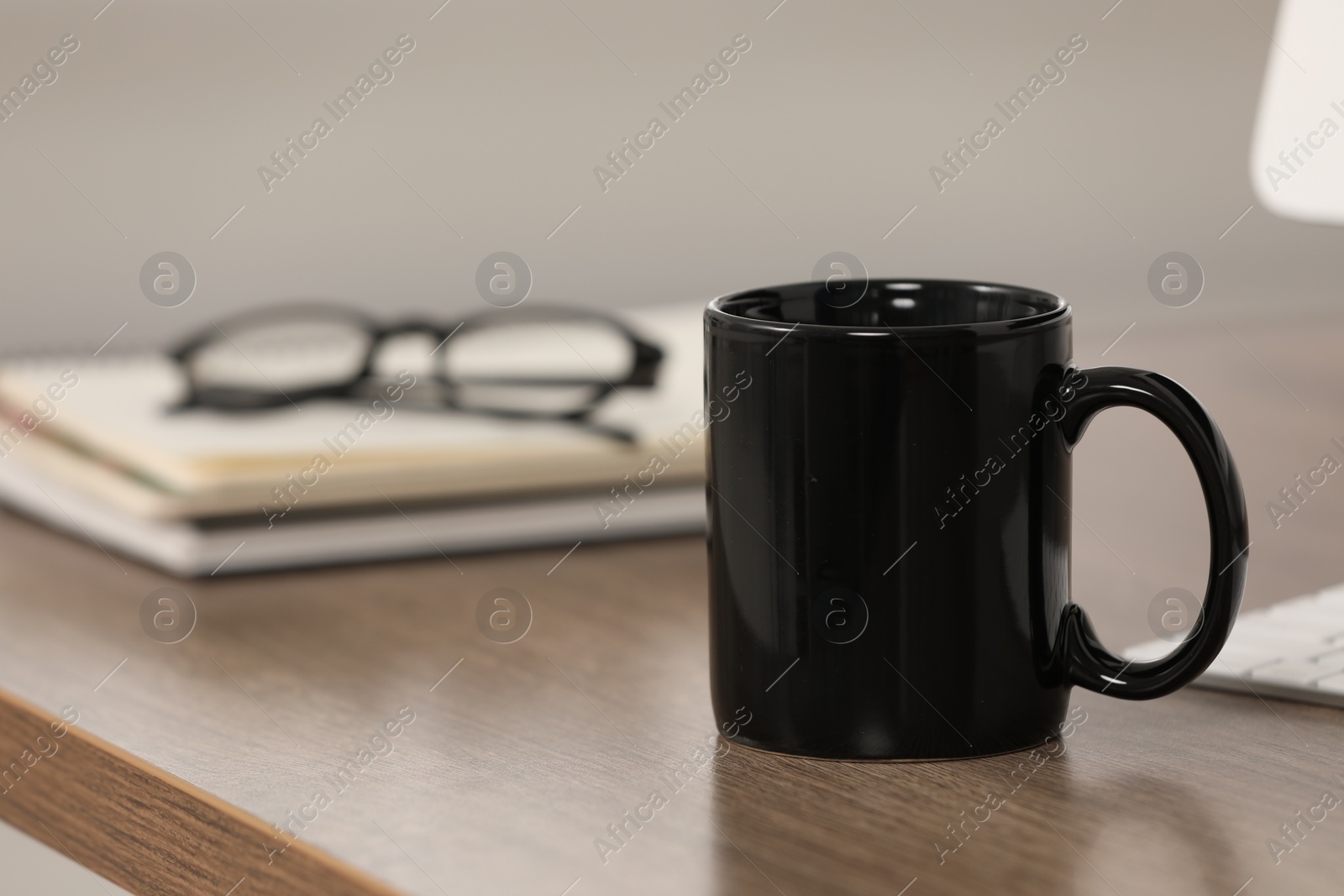 Photo of Black ceramic mug and notebooks on wooden table at workplace. Space for text