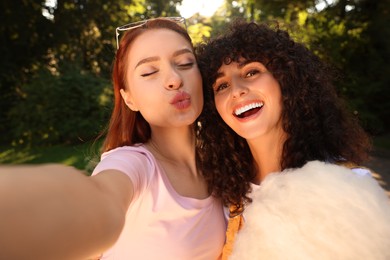 Happy friends with cotton candy taking selfie outdoors