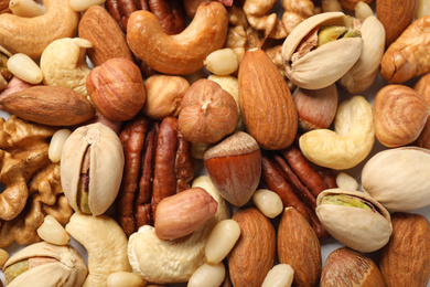 Photo of Different delicious nuts as background, closeup view