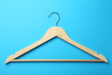 Photo of Wooden hanger on light blue background, top view