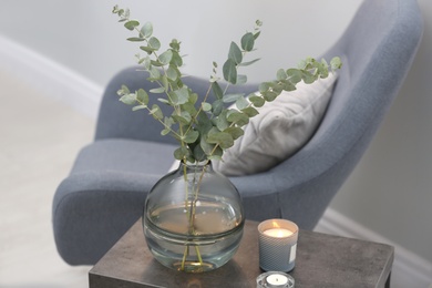 Photo of Vase with fresh eucalyptus branches on table in living room. Interior design