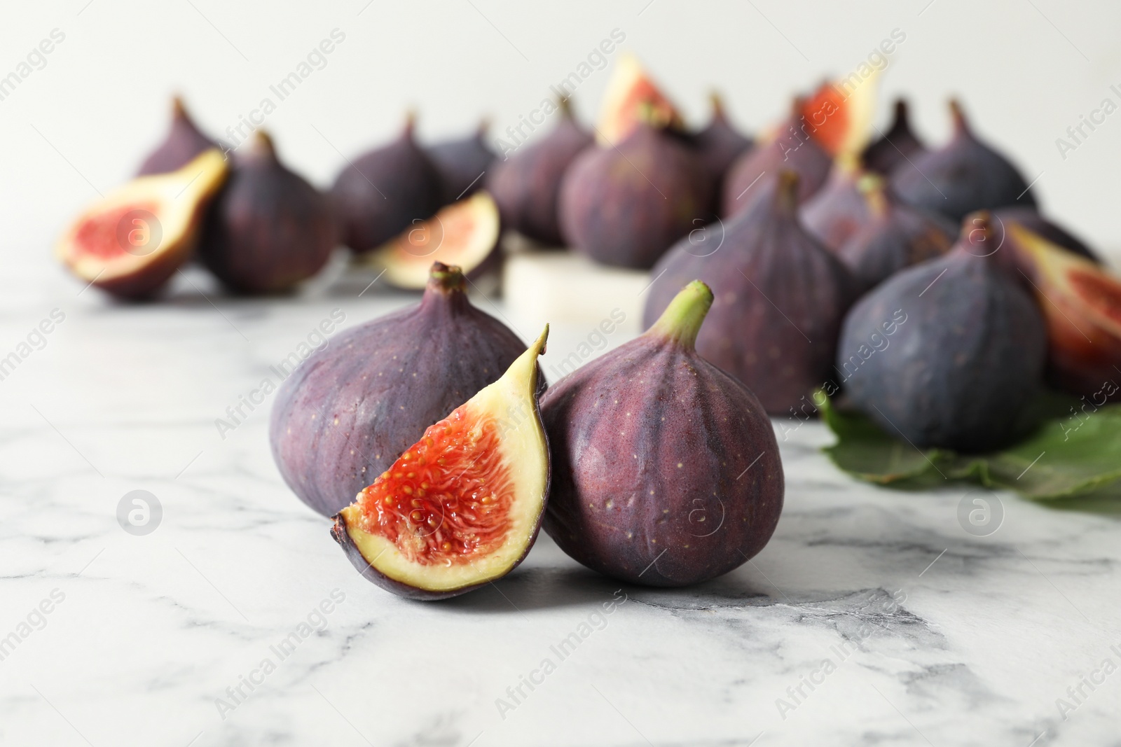 Photo of Whole and cut tasty fresh figs on white marble table