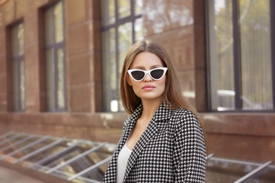 Photo of Young woman wearing stylish sunglasses on city street