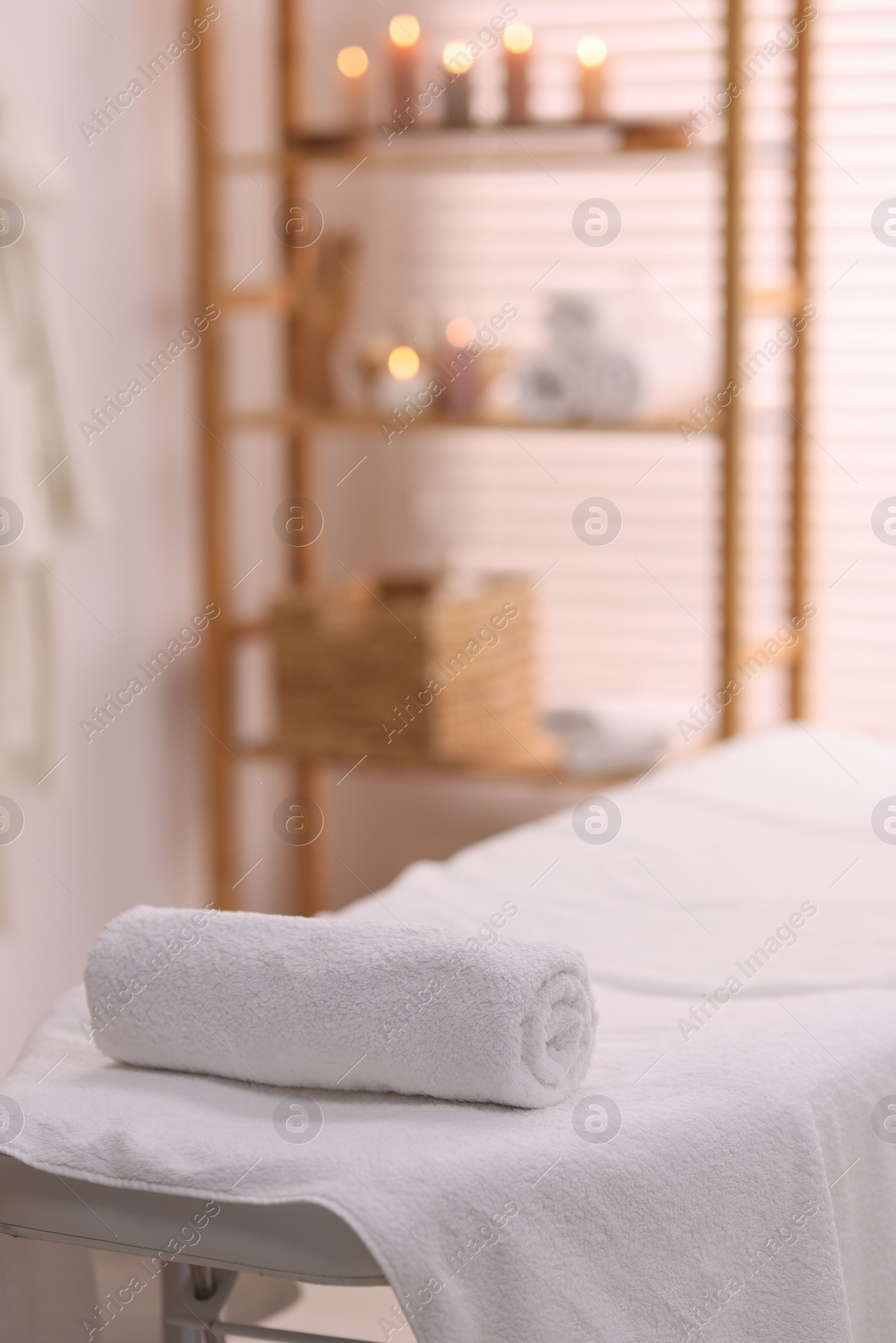 Photo of Rolled towel on massage table in spa center. Space for text