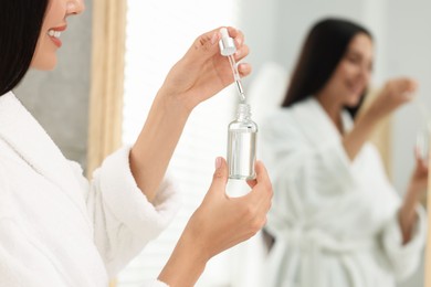 Photo of Woman holding bottle of serum indoors, closeup. Cosmetic product