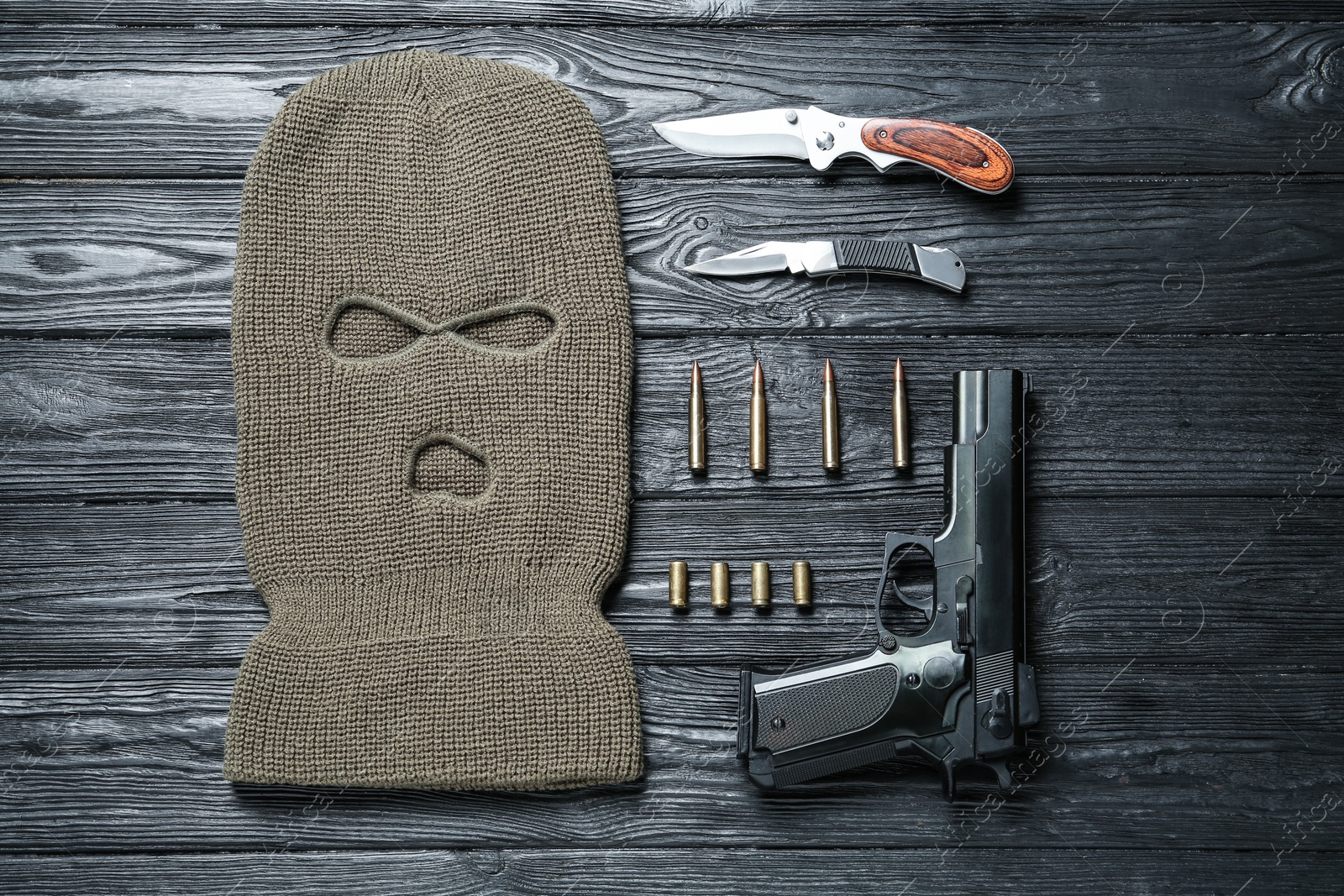 Photo of Flat lay composition with balaclava and weapons on black wooden table