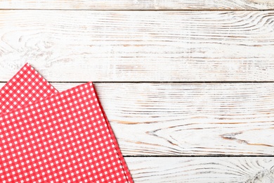 Checkered picnic blanket on wooden background, top view. Space for text