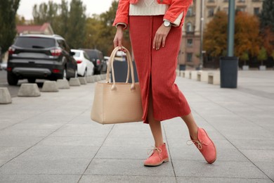 Photo of Stylish woman with trendy leather bag on city street, closeup
