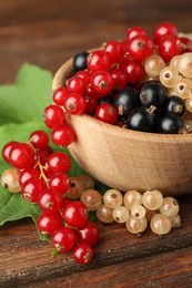 Photo of Different fresh ripe currants on wooden table, closeup