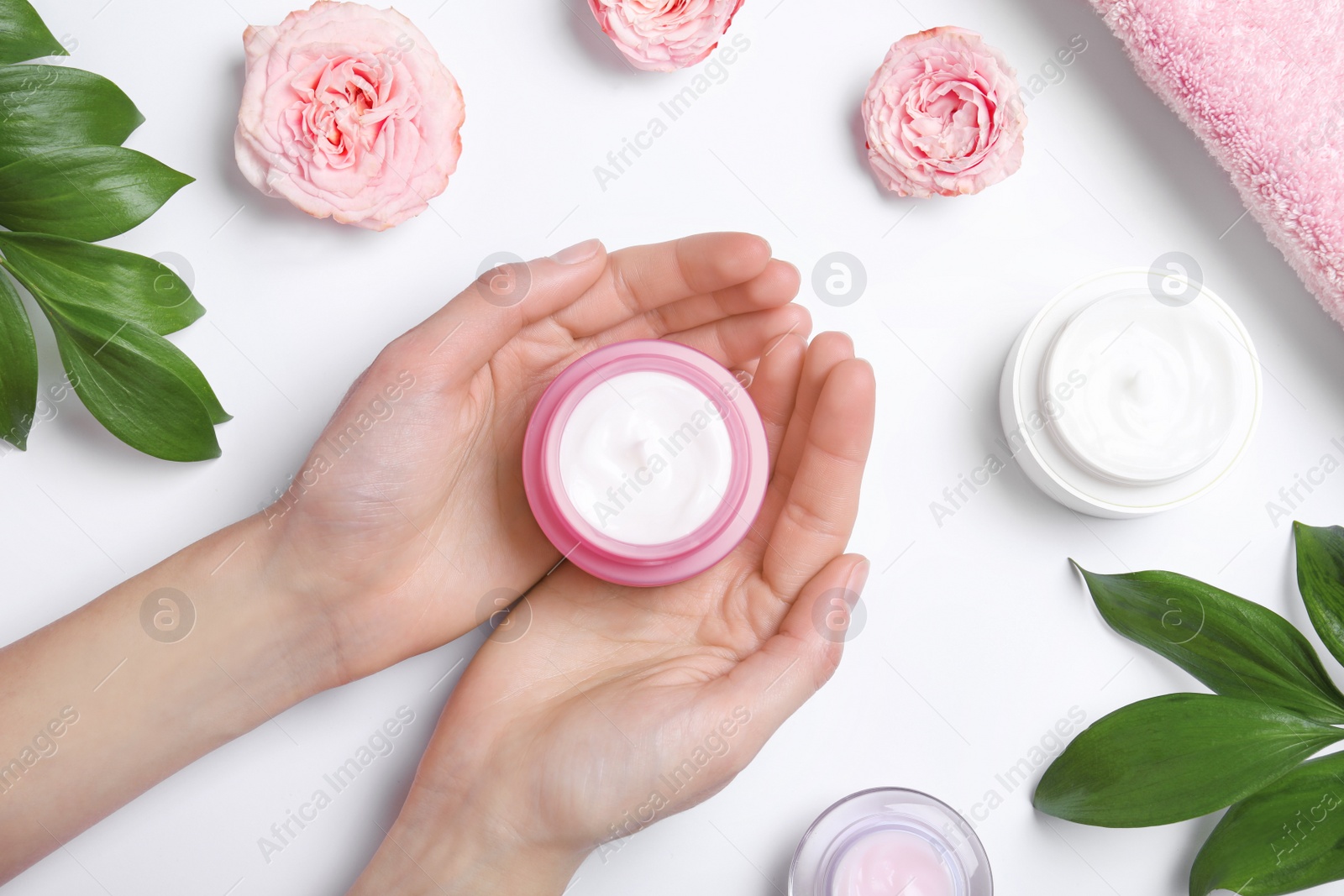 Photo of Woman holding jar of cream at white background, top view