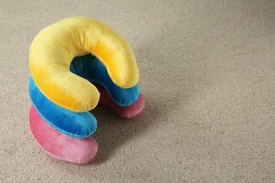 Photo of Colorful travel pillows on beige rug, space for text