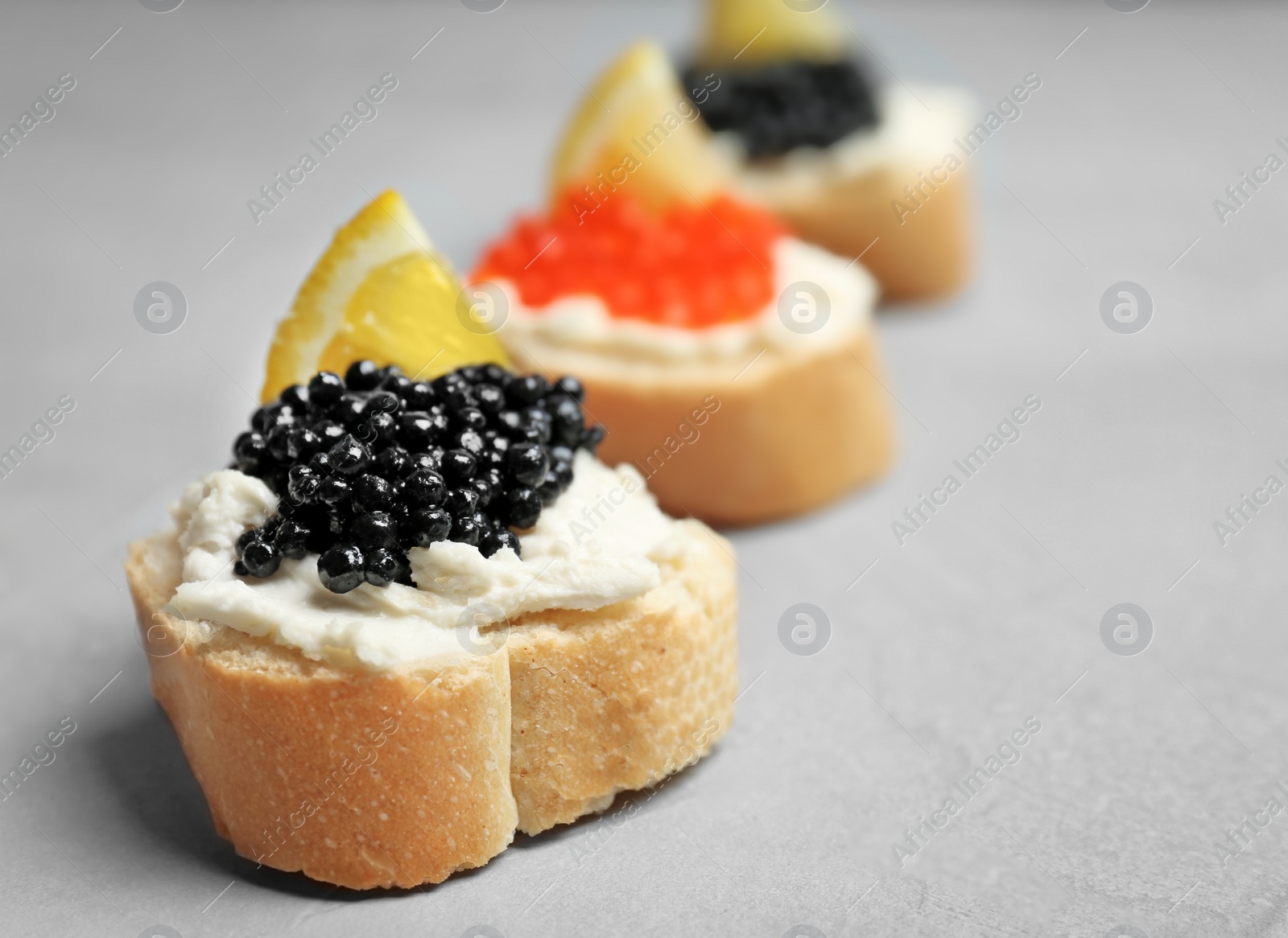 Photo of Sandwiches with black and red caviar on grey background