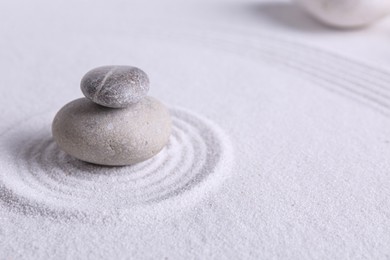 Photo of Zen garden stones on white sand with pattern, space for text