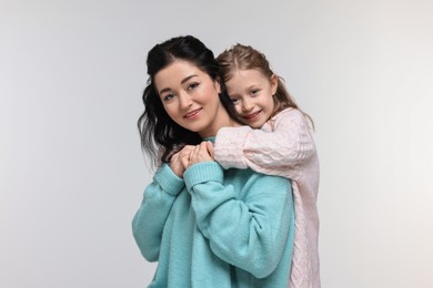 Beautiful mother hugging with little daughter on white background