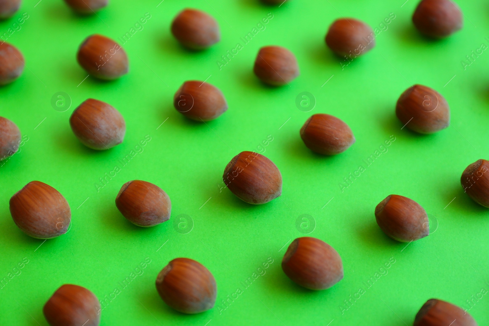 Photo of Brown tasty hazelnuts on green background, closeup
