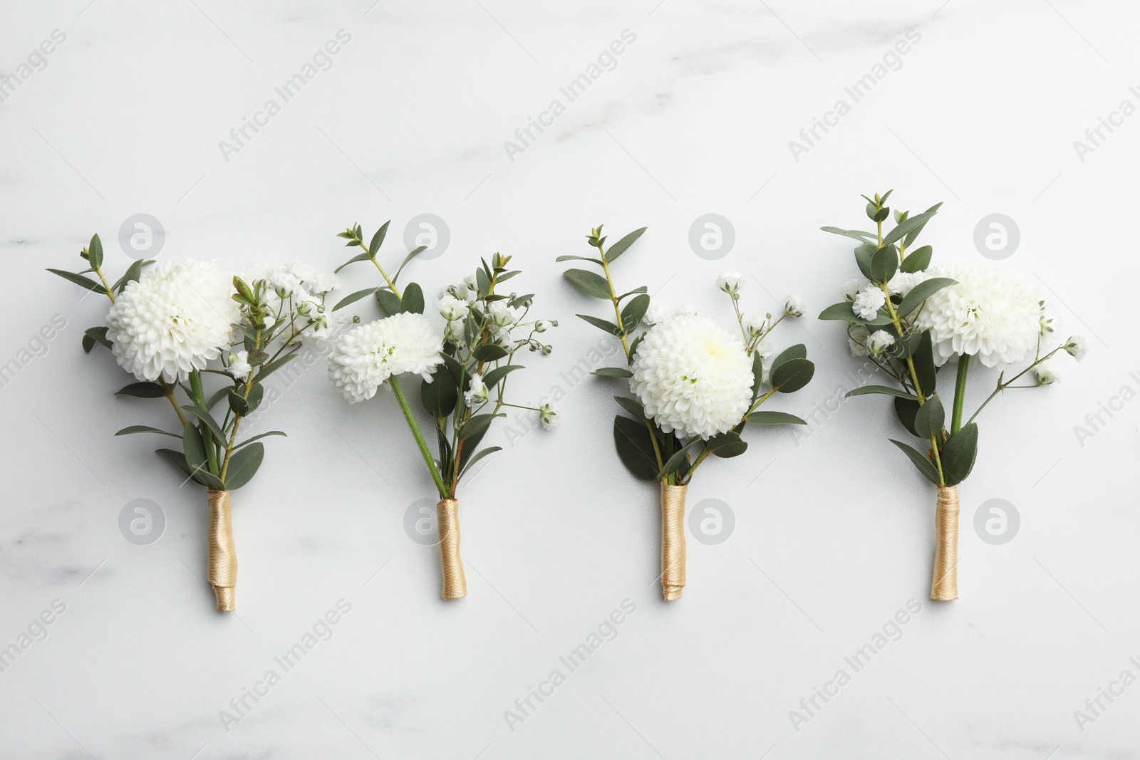 Photo of Small stylish boutonnieres on white marble table, flat lay