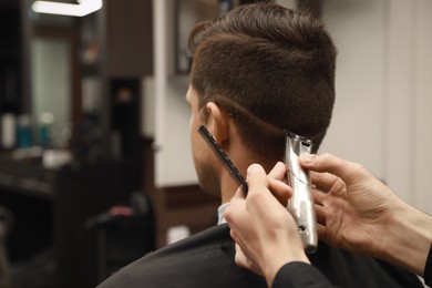 Photo of Professional hairdresser making stylish haircut in salon, closeup