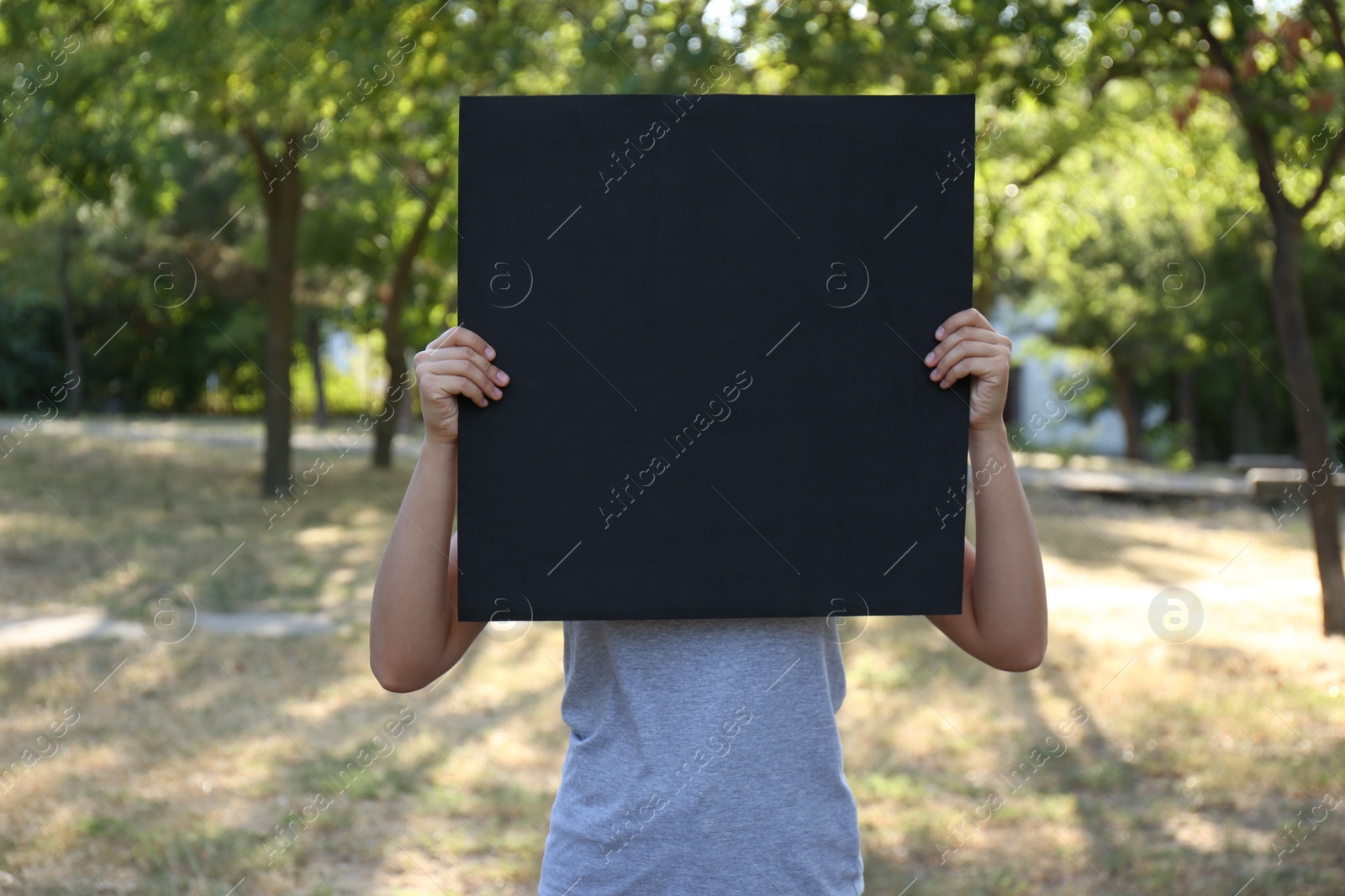 Photo of Woman holding blank poster outdoors. Mockup for design