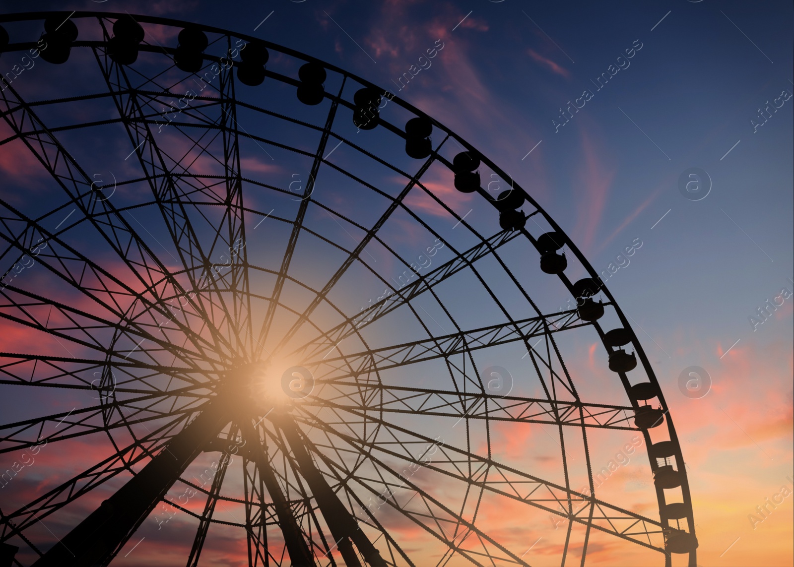 Image of Beautiful large Ferris wheel outdoors at sunset, low angle view