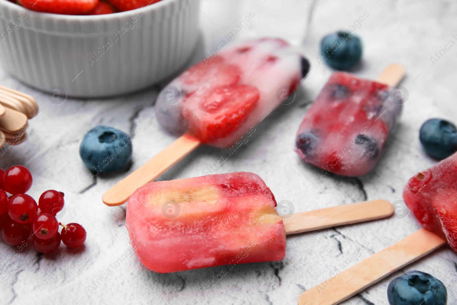 Photo of Tasty fruit and berry ice pops on light table, closeup