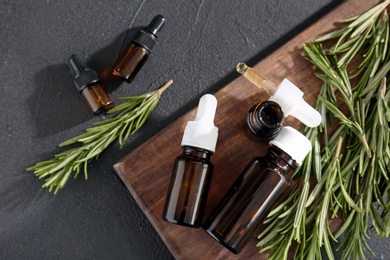 Photo of Bottles of rosemary essential oil on dark background