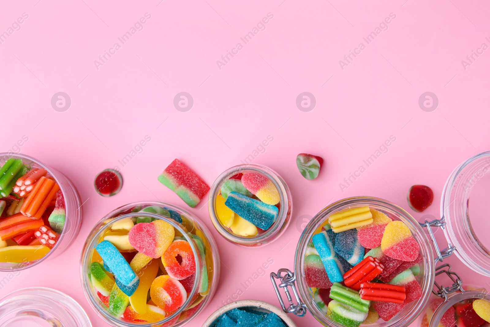 Photo of Tasty jelly candies in jars on orange background, flat lay. Space for text