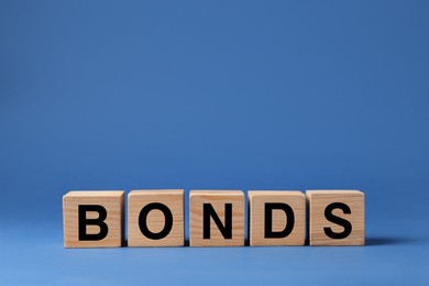 Photo of Word Bonds made of wooden cubes with letters on blue background