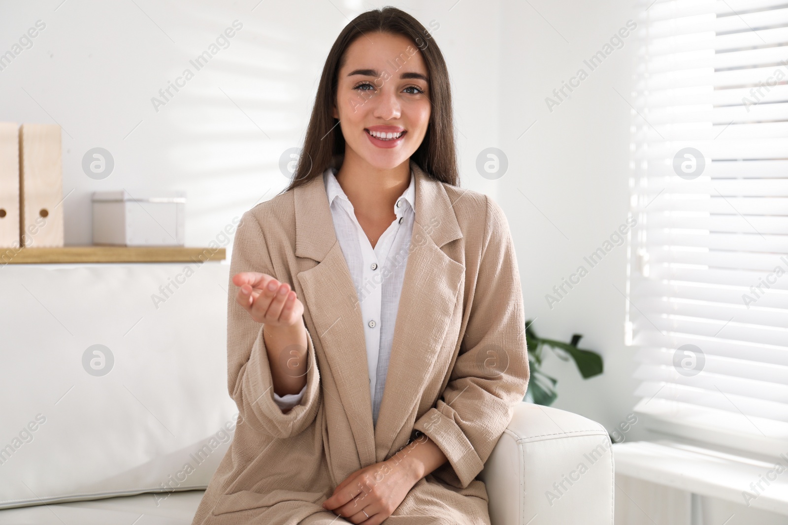 Photo of Young woman talking with her coworkers on video call indoors, view from web camera