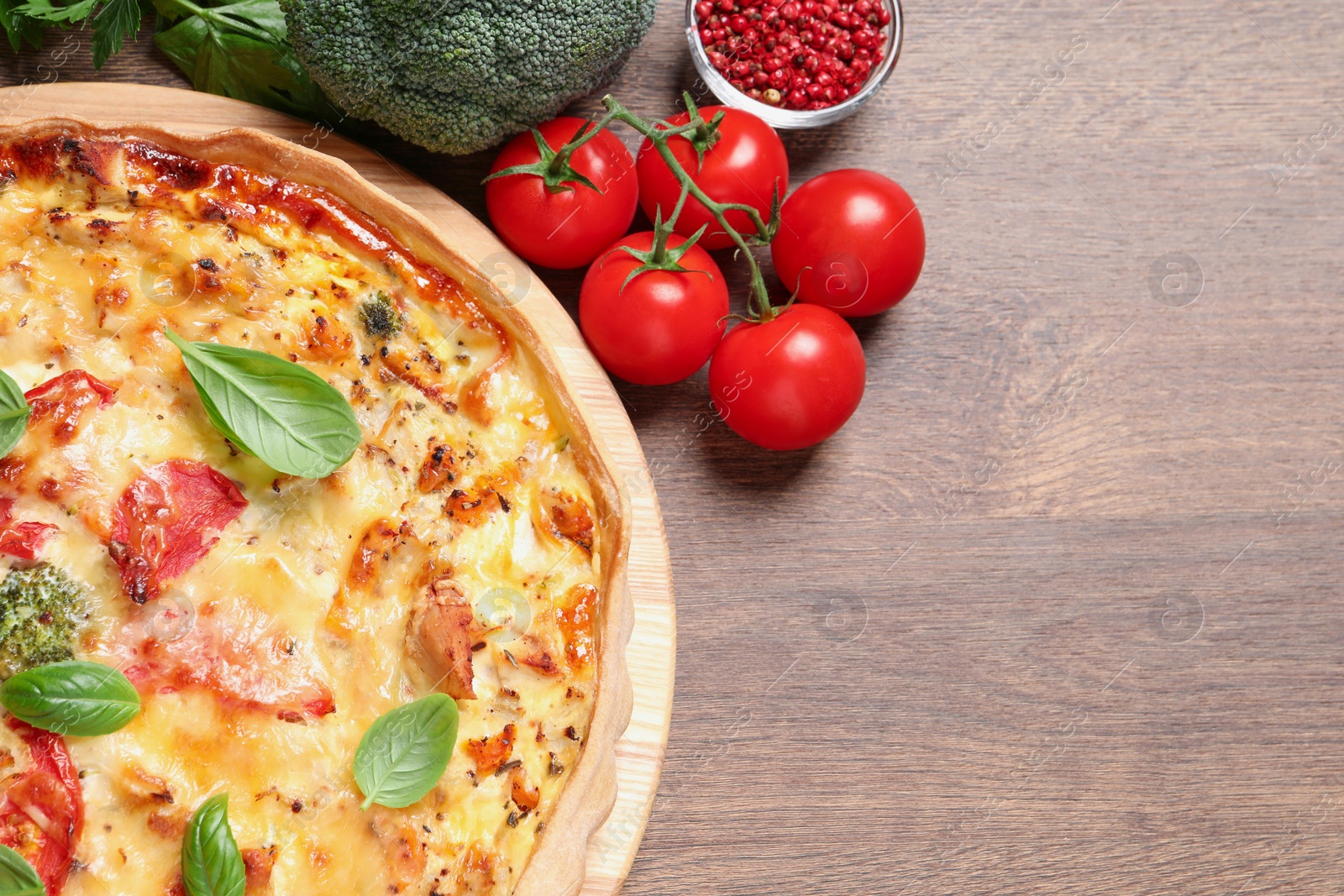 Photo of Tasty cheese quiche and ingredients on wooden table, flat lay. Space for text