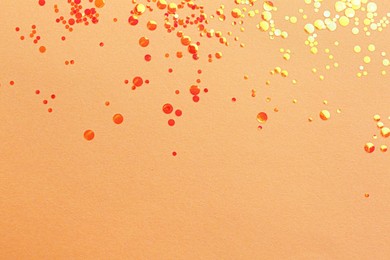Photo of Shiny bright orange glitter on beige background, flat lay. Space for text