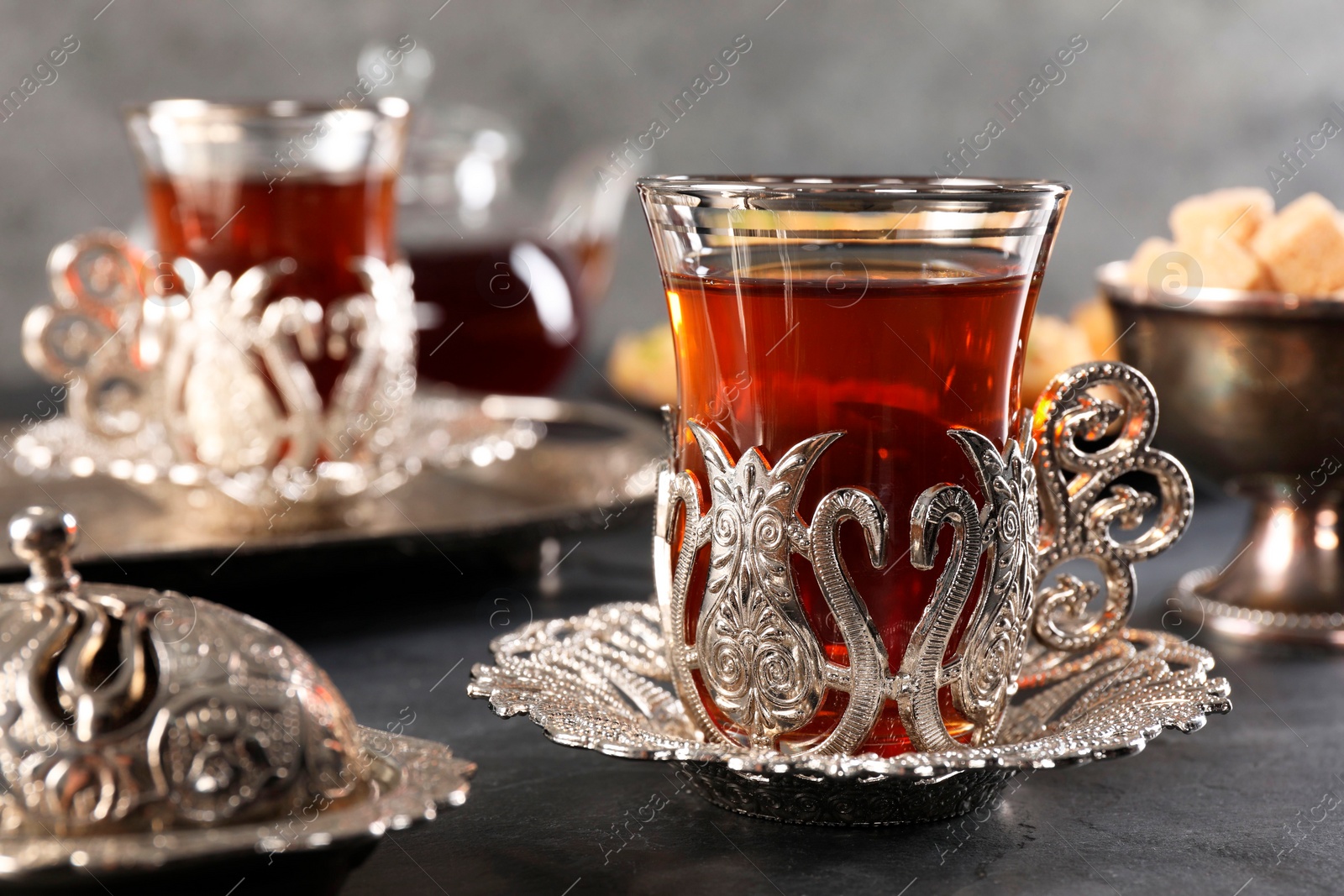 Photo of Traditional Turkish tea served in vintage tea set on black table, closeup