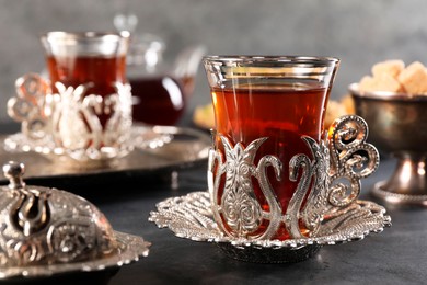 Photo of Traditional Turkish tea served in vintage tea set on black table, closeup