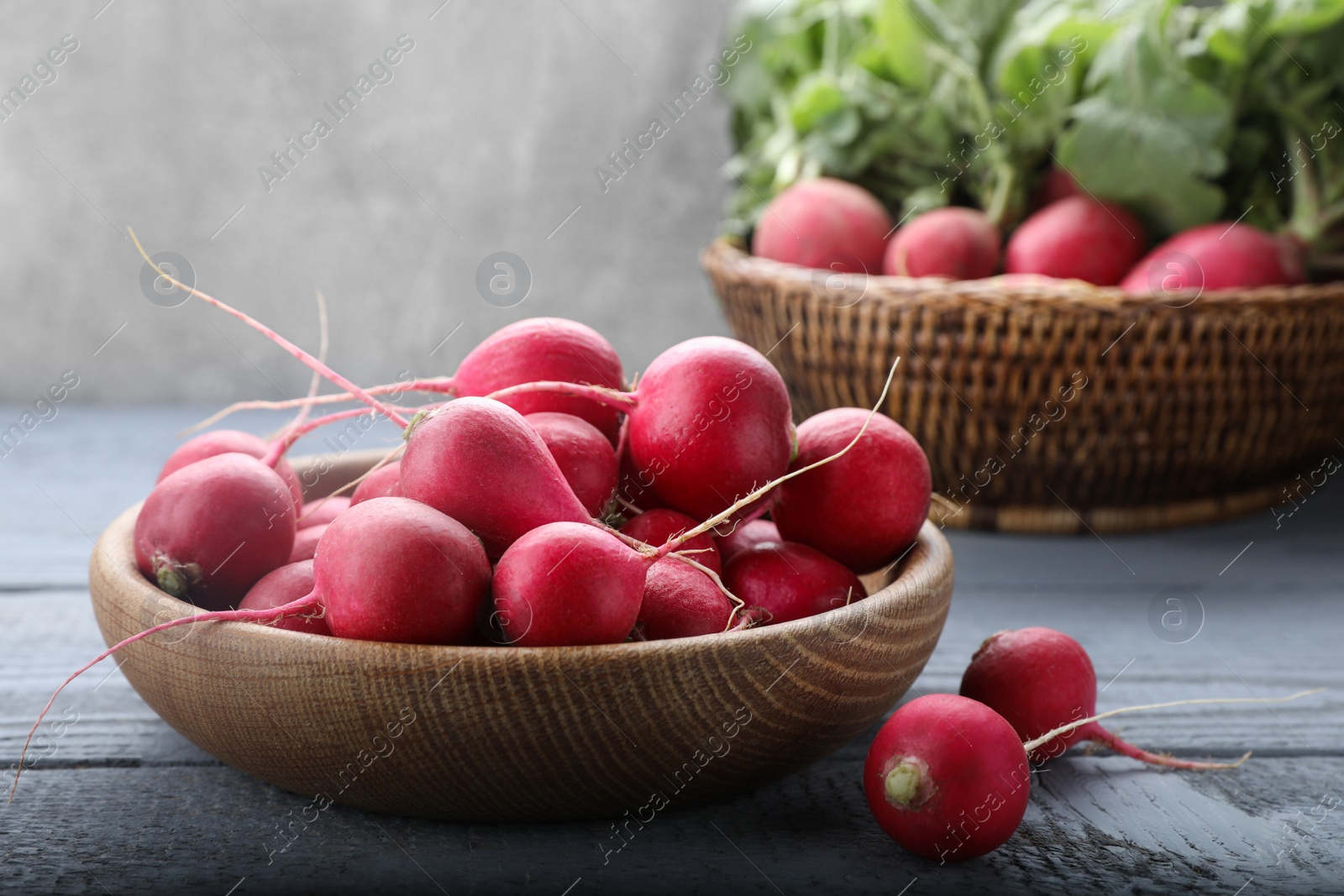 Photo of Bowl with fresh ripe radishes on grey wooden table