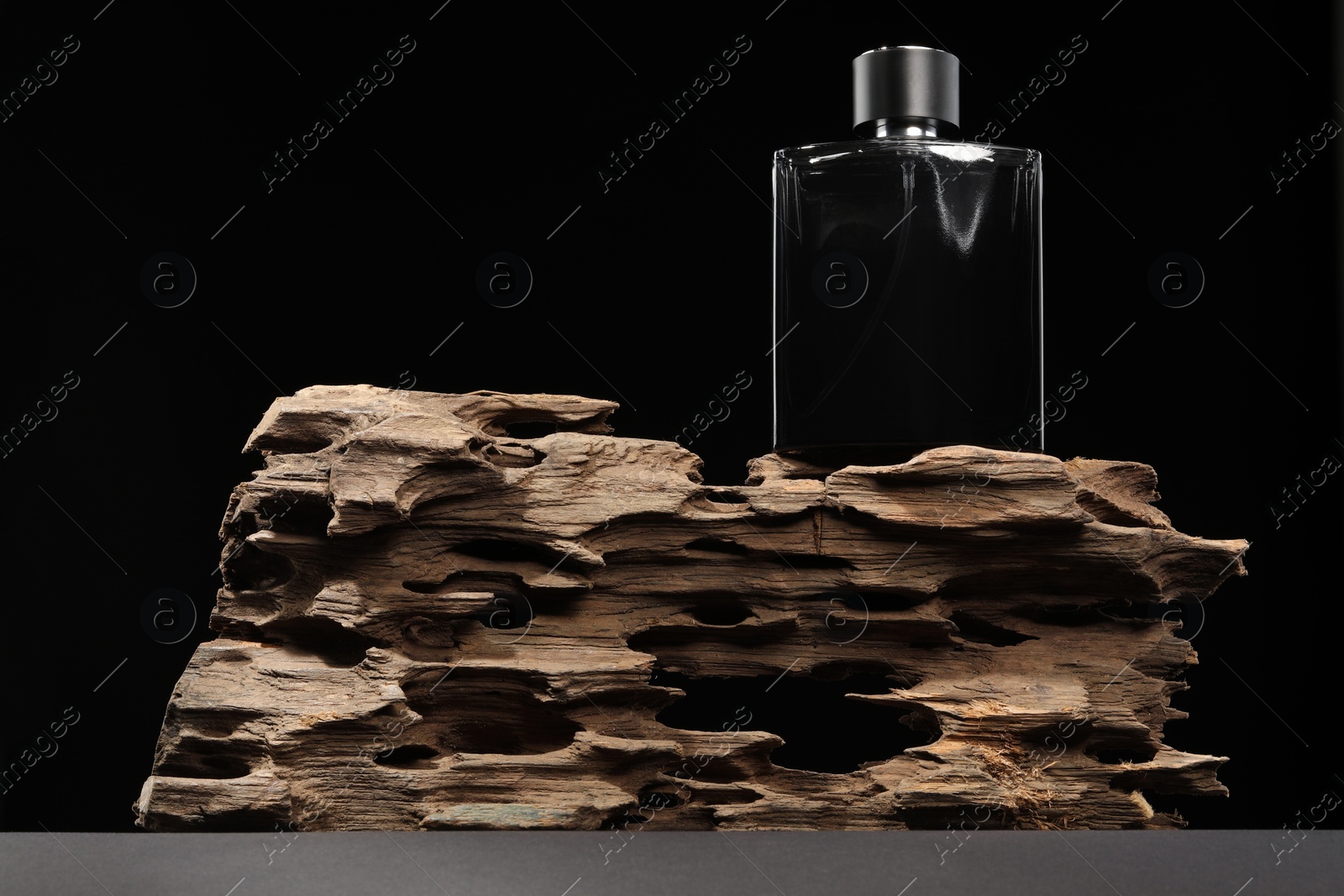 Photo of Luxury men`s perfume in bottle on grey table against black background, low angle view