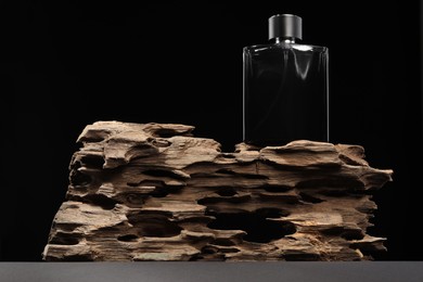 Luxury men`s perfume in bottle on grey table against black background, low angle view