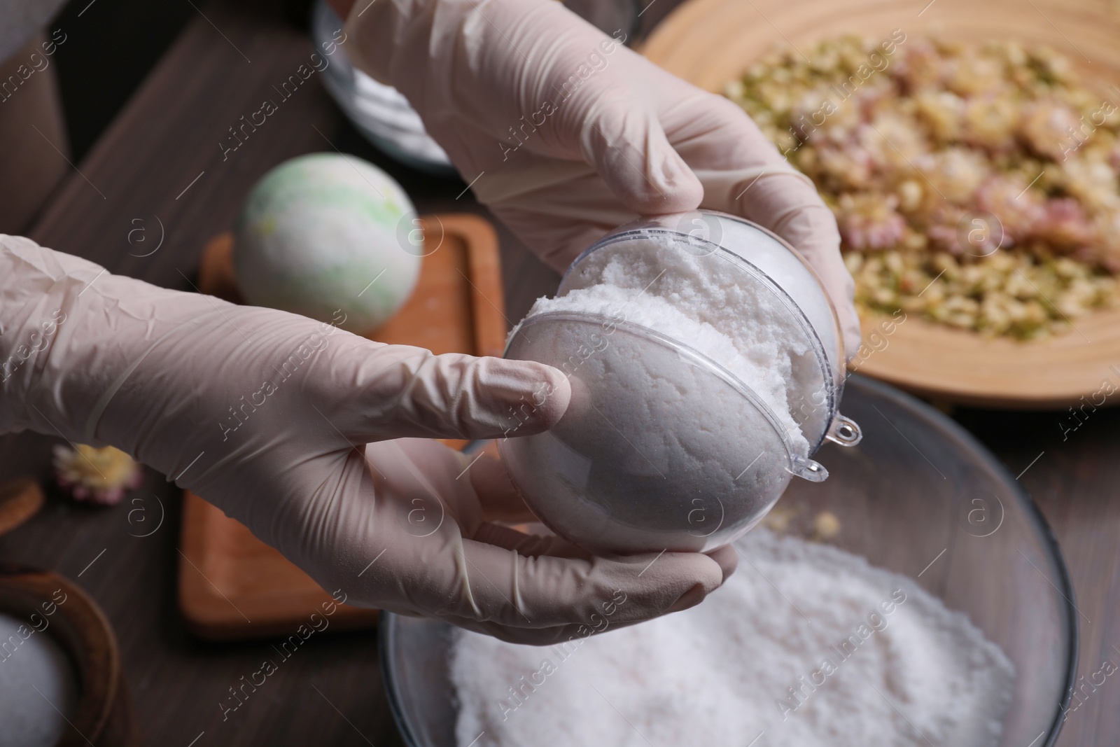 Photo of Woman in gloves making bath bomb at table, closeup