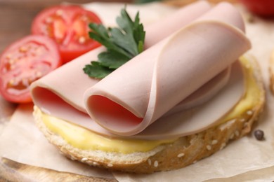 Delicious sandwich with boiled sausage and cheese on board, closeup