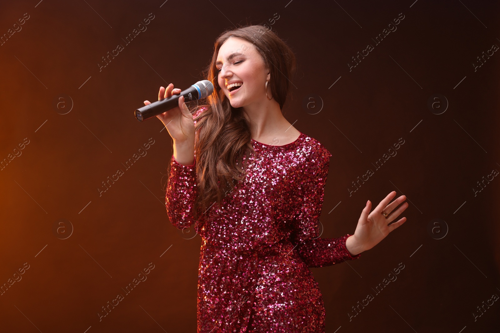 Photo of Emotional woman with microphone singing in color lights