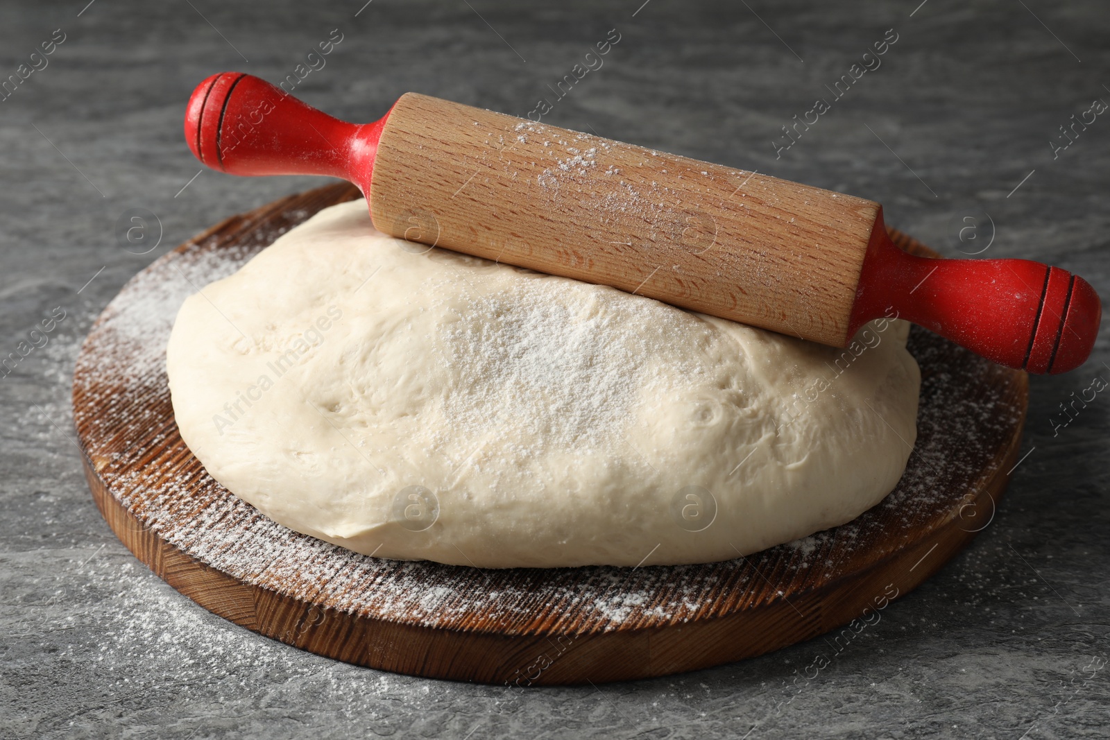 Photo of Raw dough and rolling pin on grey table