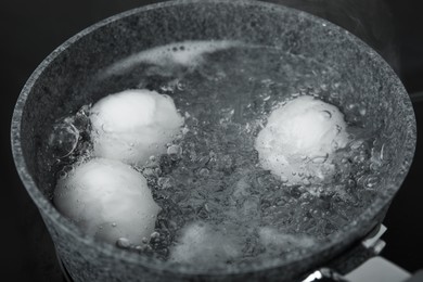 Photo of Boiling chicken eggs in saucepan on electric stove, closeup