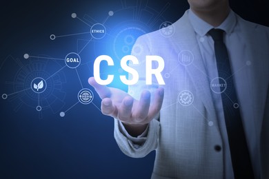 Image of Corporate social responsibility concept. Man demonstrating digital scheme with word CSR on blue background