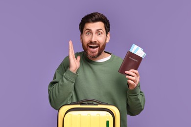 Emotional man with passport, tickets and suitcase on purple background