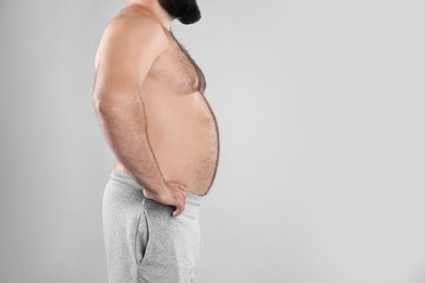 Fat man on grey background, space for text. Weight loss